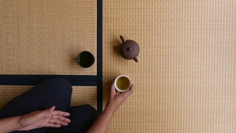 hombre bebiendo té tradicional japonés mientras está sentado en el suelo de tatami - tiro medio