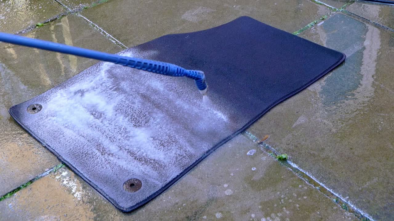Applying cleaner to large carpet foot with a blue pressure sprayer - close up
