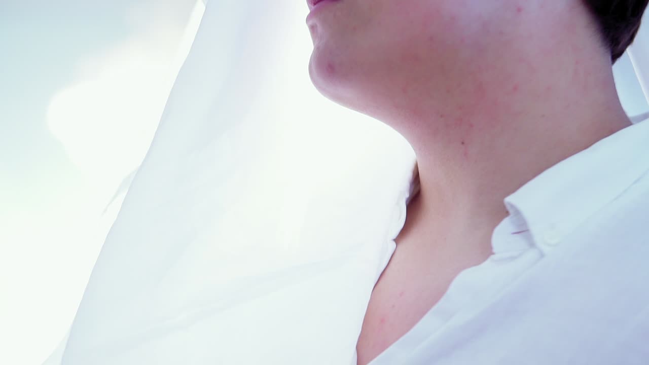 toma cinematográfica de una persona caucásica con una elegante camisa blanca y un fondo iluminado