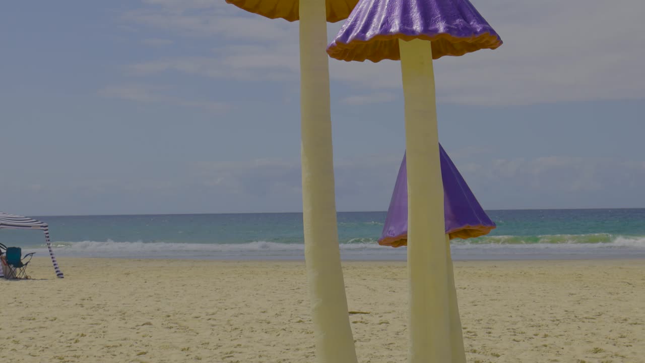esculturas de hongos coloridos en una playa de arena