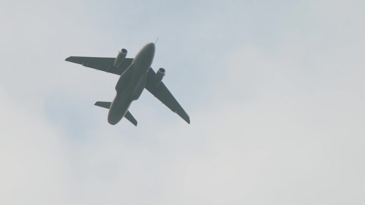 Modern twin jet military transport aircraft flies overhead in misty gray skies during multinational Falcon Leap exercise over Oosterbeek Netherlands in upward shot.