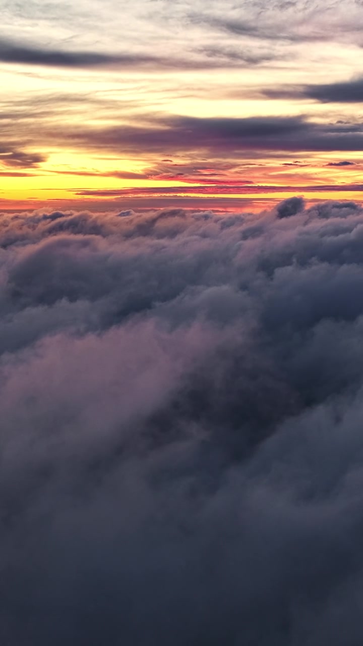 Colorful sunset sky with red and orange hues above dense clouds.