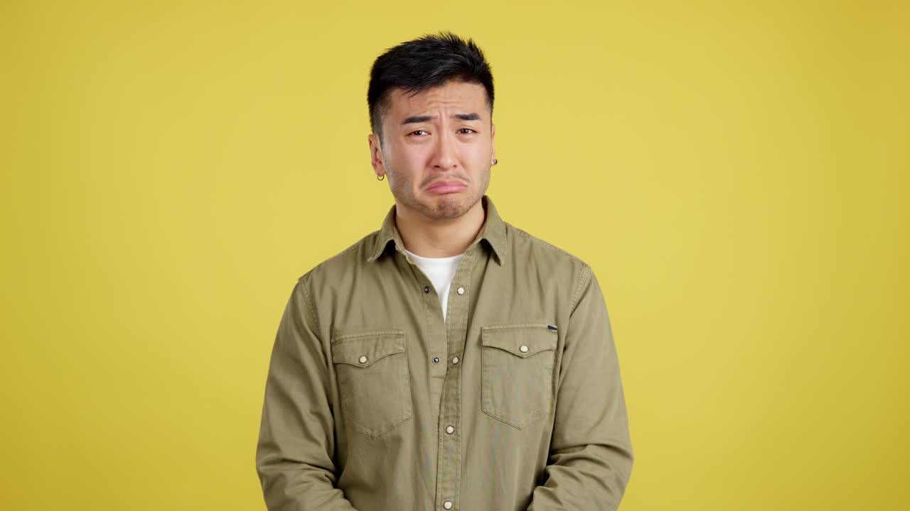 A sad and upset man crying with a pained expression on a yellow background