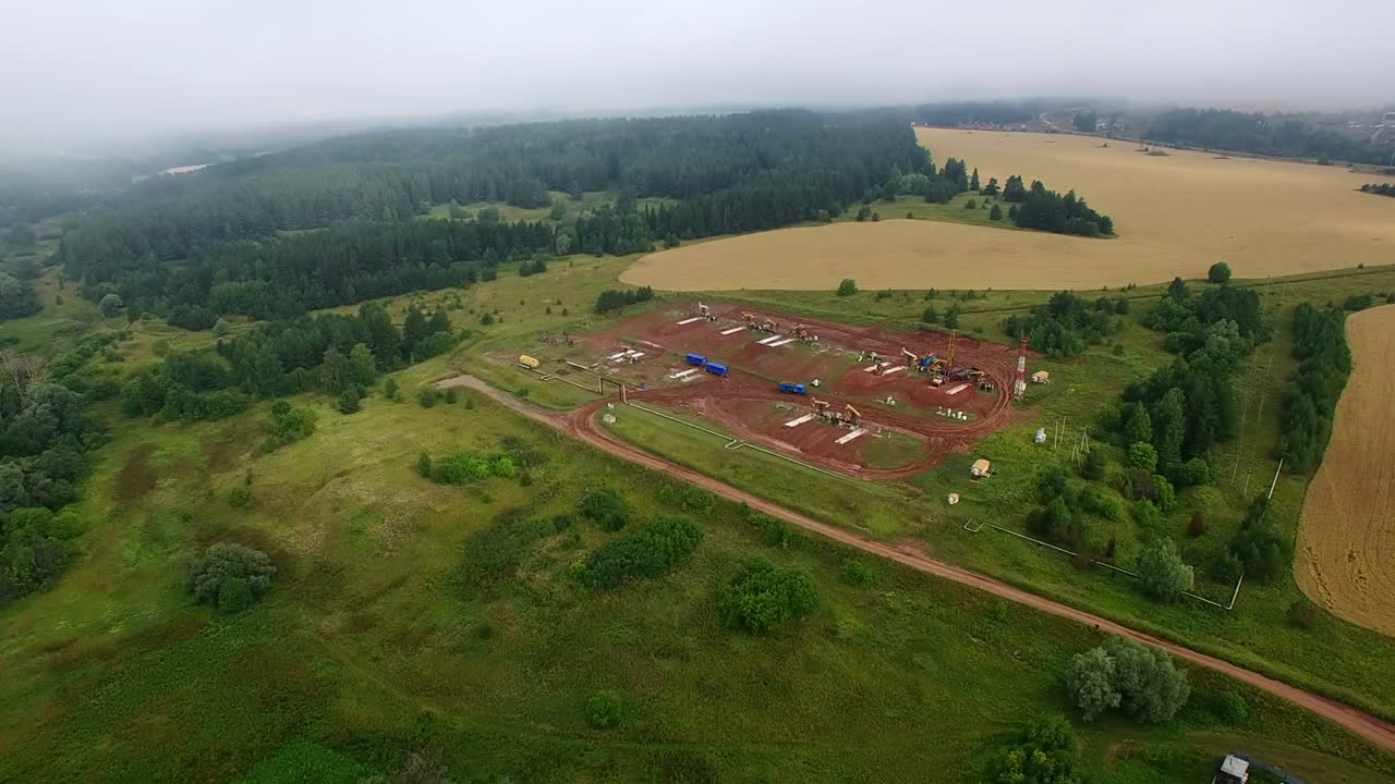 panorama nebuloso aéreo de las bombas de petróleo en el clúster de campos petrolíferos. mañana de verano, las bombeas de petróleo de trabajo y la plataforma de perforación entre la niebla.