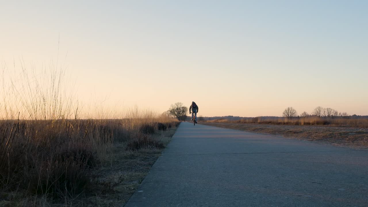 해가 지는 시골 도로 에서 자전거 타는 사람