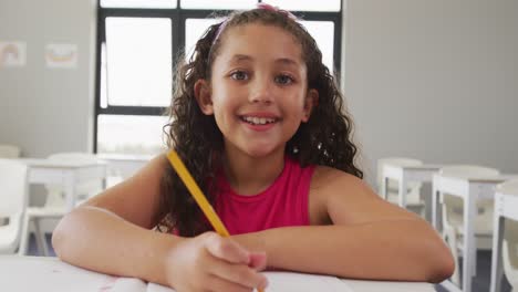 Video-Eines-Glücklichen-Gemischtrassigen-Mädchens,-Das-An-Der-Schulbank-Sitzt-Und-Lernt