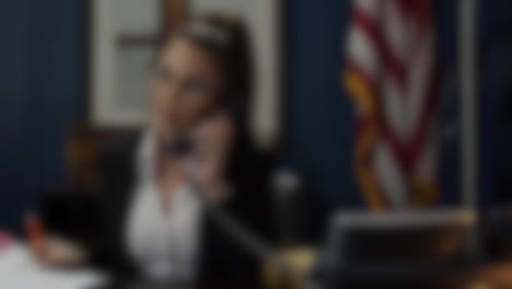 Blurred-shot-of-secretary-on-the-phone-with-the-flag-of-the-United-States-of-America-in-the-background,-state-representatives-concept