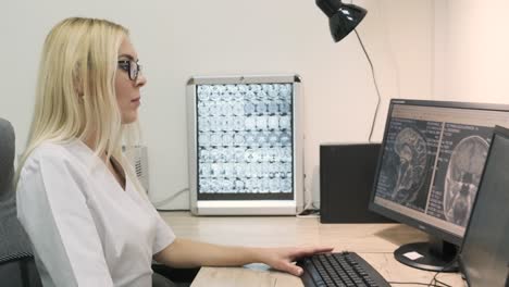 professional female doctor radiologist examines brain ct or mri scan results, working on a computer screen at her personal desk at hospital