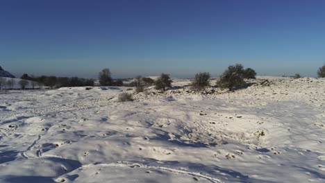 snow covered rural winter countryside track footprint shadows terrain aerial view low forward orbit right