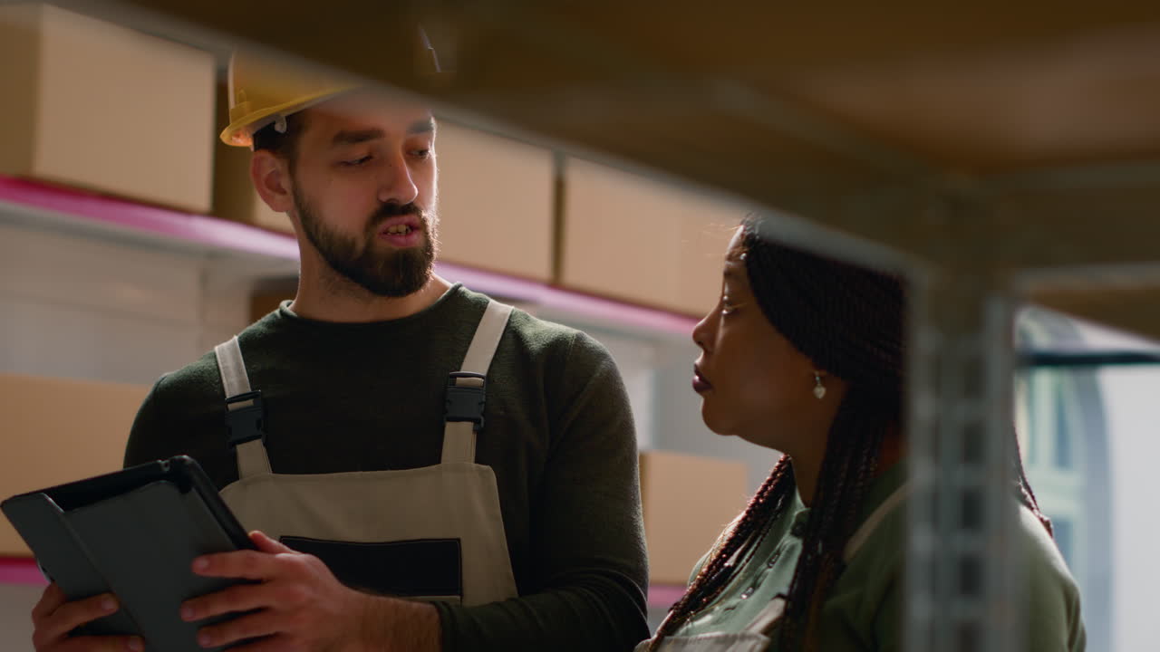 Warehouse workers discussing inventory with a tablet