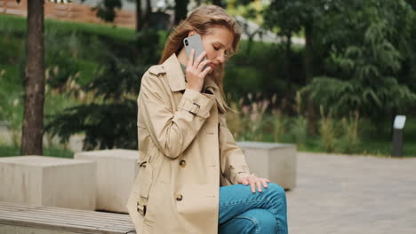 caucasian female student talking on the phone outdoors.