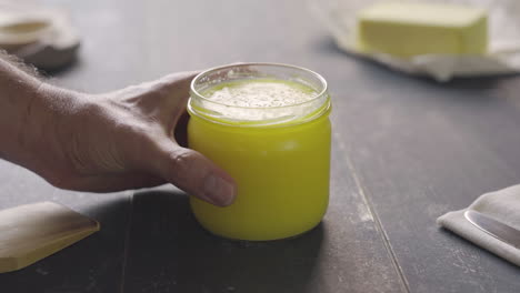 man's hand takes pot of ghee butter