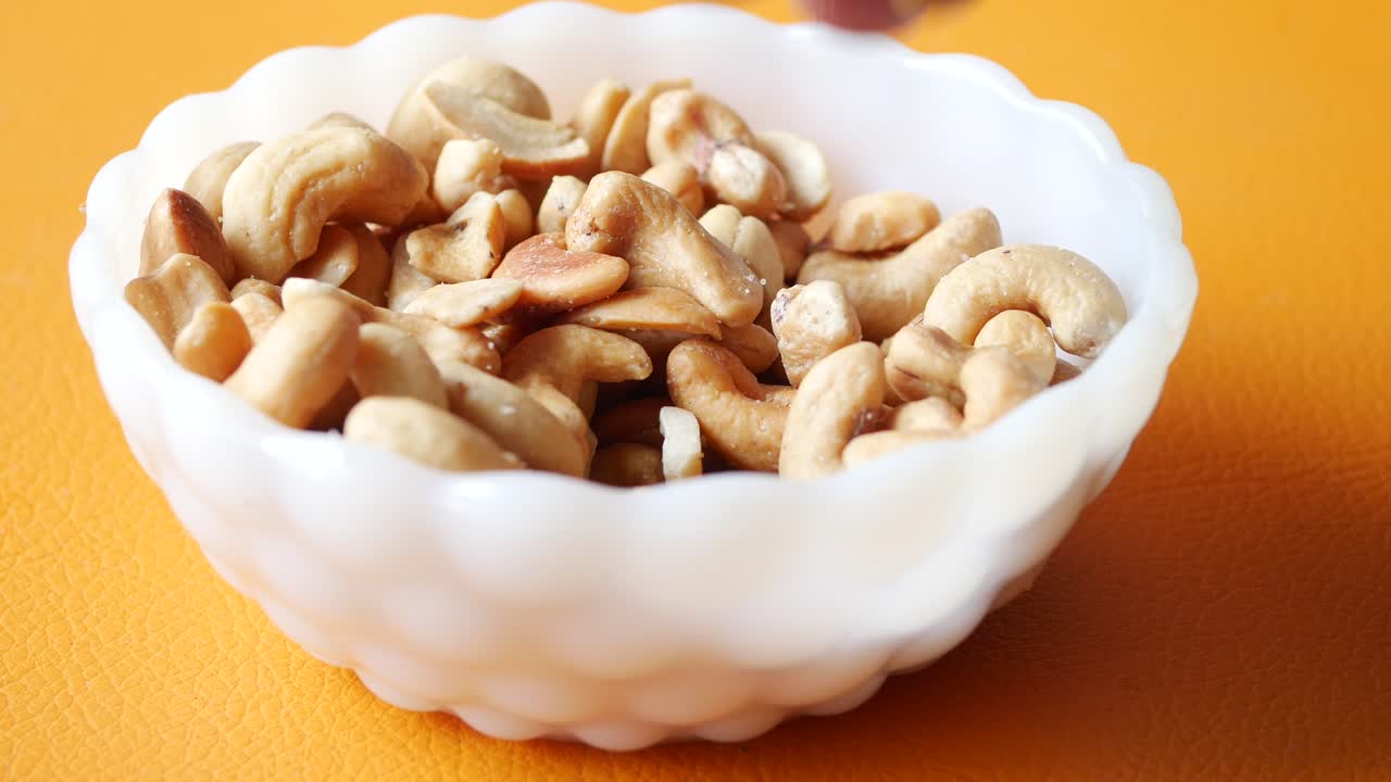 Hand pick a cashew nut from a bowl ,