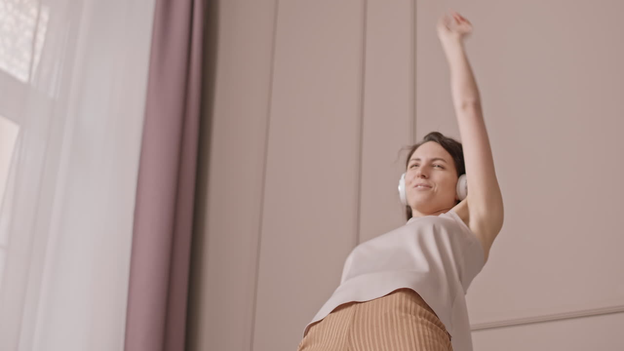 Woman dancing with headphones in bedroom