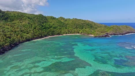 aerial over idyllic clear blue water with visible coral reef, playa ermitano