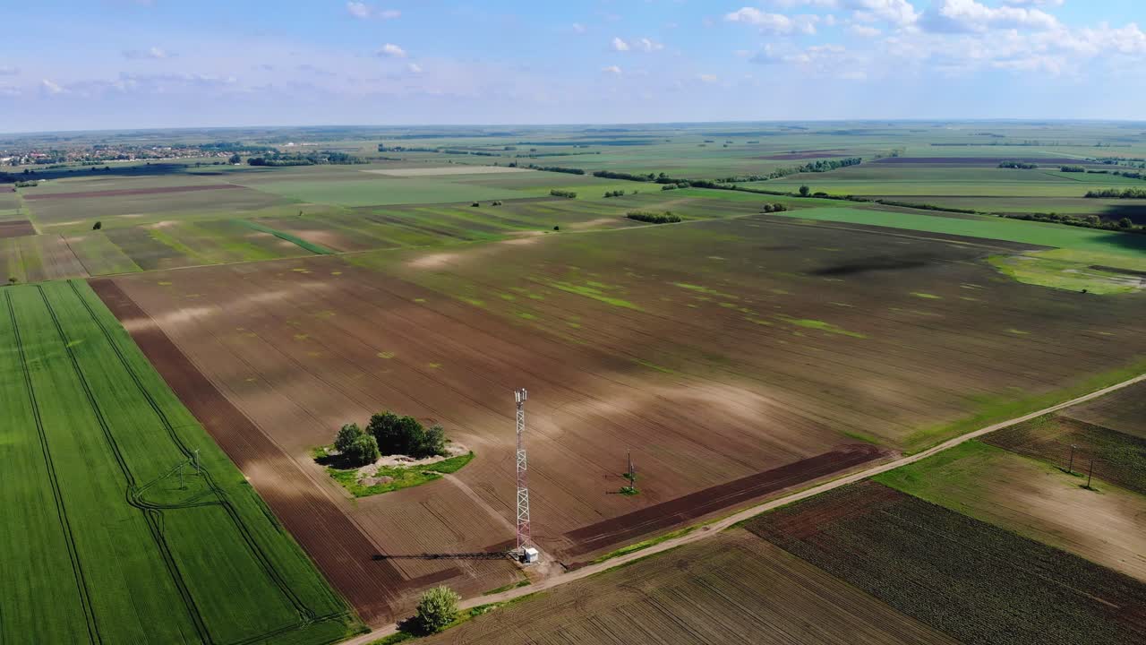 Flying over a cellphone tower on the field on a sunny day