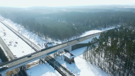aerial shot of driving cars on bridge over railroad line during winter and sunlight