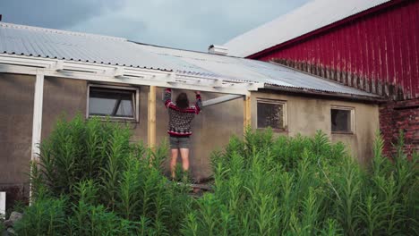 worker mounting polycarbonate roof sheet on extension roofing frame outside the house