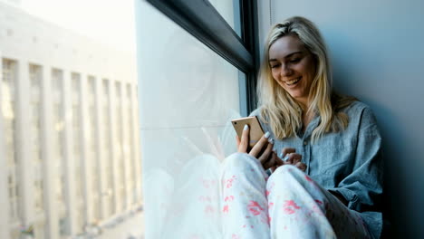 mulher usando telefone móvel perto da janela 4k