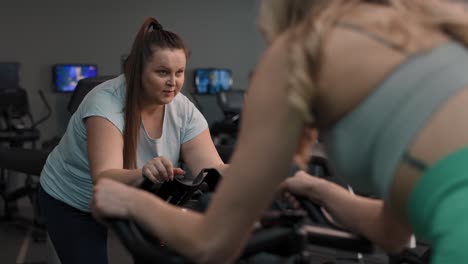 Two-caucasian-women-ride-a-bikes-at-the-gym.