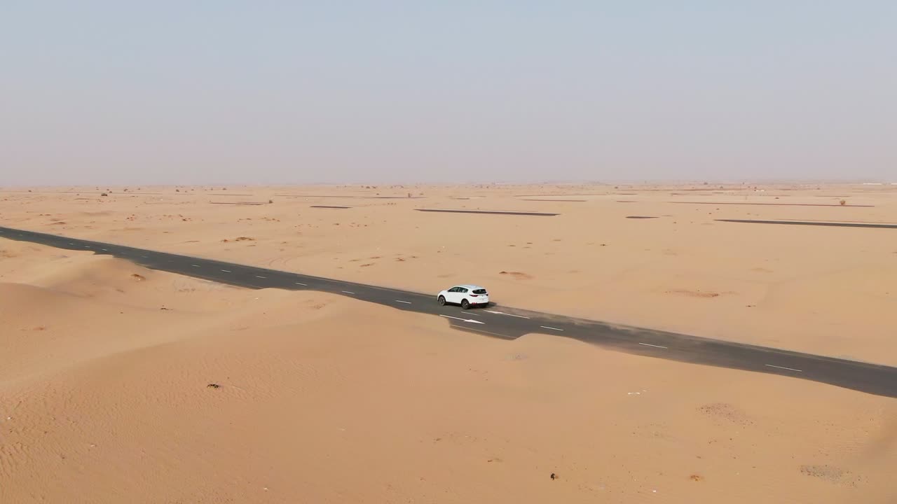coche blanco conduciendo en una carretera a través del desierto