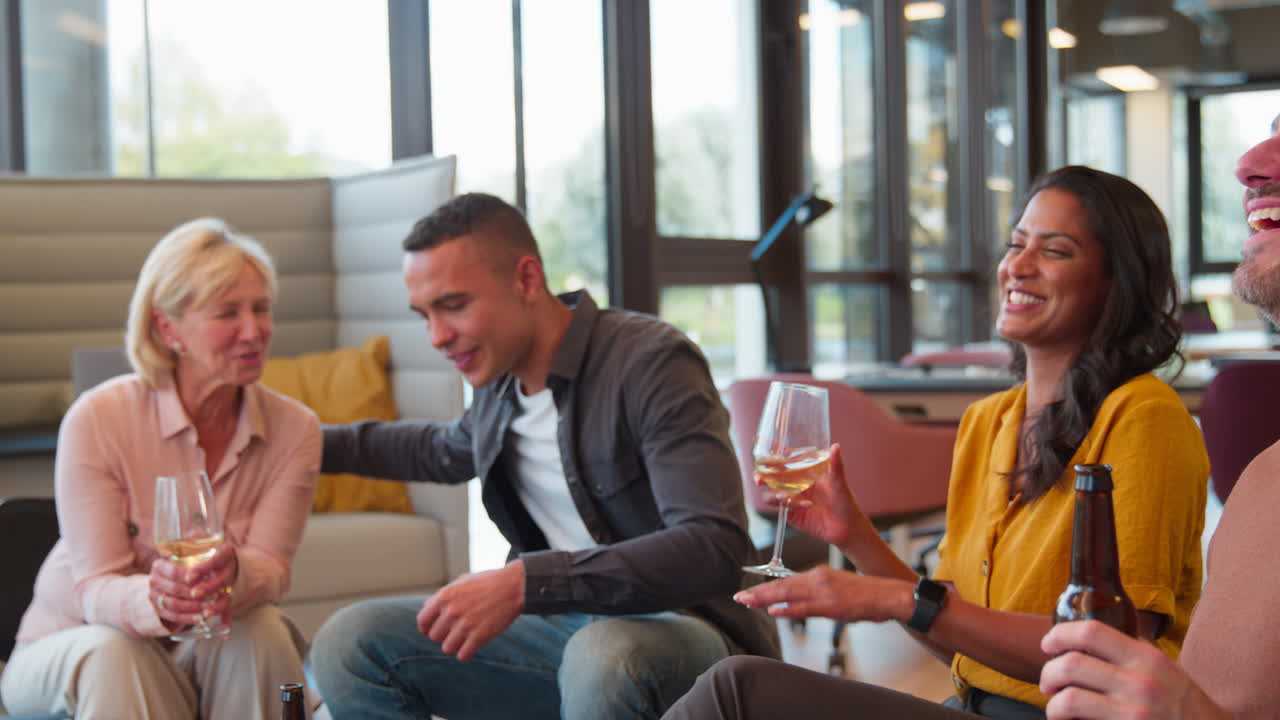 직원 들 이 사무실 에서 비공식적 인 모임 에서 일 후 음료 를 마시면서 건배 하고 있다