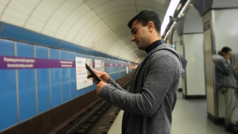 man using tablet in a subway station