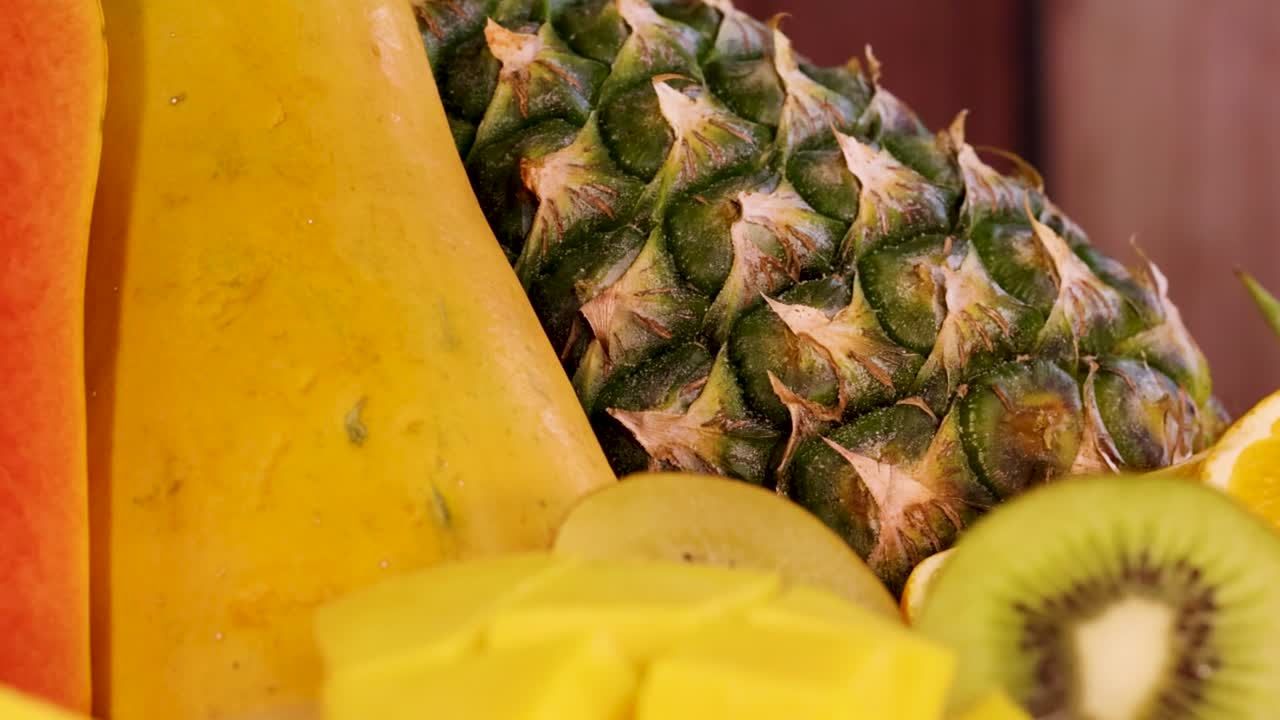 A vibrant display featuring pineapple, papaya, kiwi, orange, and mango slices.