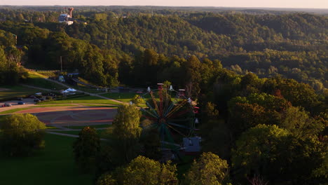 sigulda ferris wheel at festivity square; popular tourist attraction in sigulda, latvia. slow aerial rotation towards the beautiful sunset horizon over gauja valley.