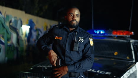 young policeman taking out gun and pointing at somebody outdoor at night