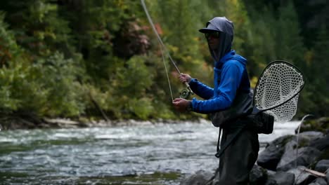 Vista-Lateral-De-Un-Joven-Pescador-Caucásico-Pescando-En-El-Arroyo-Del-Bosque-En-Un-Día-Soleado-4k