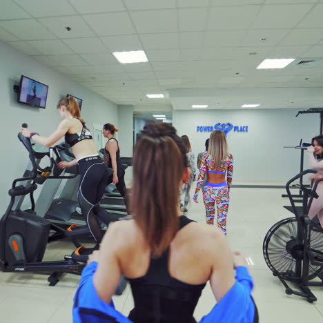group of young sporty women at the end of workout in a sports club. beautiful females in sport clothes going out of a fitness center after hard training on the modern simulators.