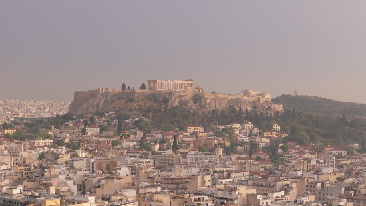 Aerial establishing of the Acropolis in Athens during daylight over urban rooftops, ascend backdrop