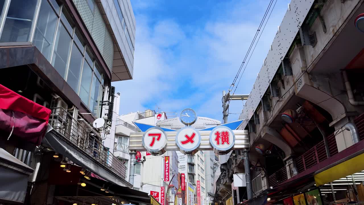 Bustling Tokyo street market under blue sky with shops and people walking by on a sunny day