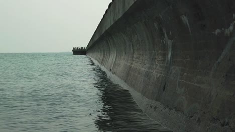 wide shot of slow moving waves lapping against a long concrete wall jutting out into lake ontario