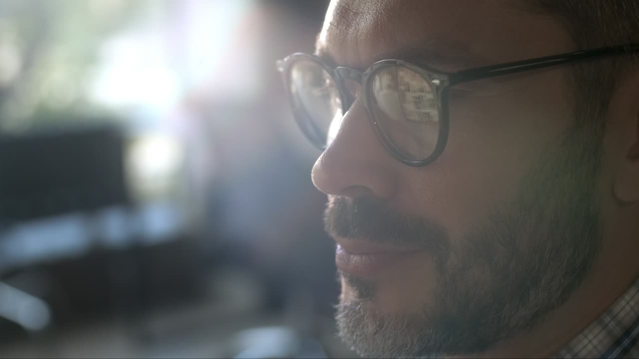 hombre con gafas mirando el monitor y navegando por internet. la pantalla del monitor se refleja en las gafas. de cerca. trabajo en la oficina de casa. trabajo remoto