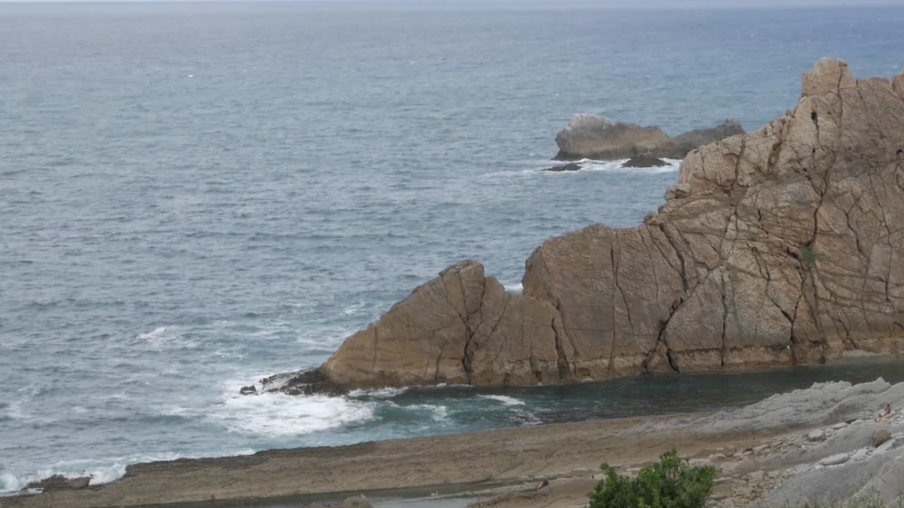 Rocky coastline with blue ocean waves at Arnia Beach, Soto de la Marina, Cantabria, Spain