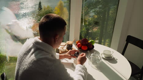 husband mixes dried tea leaves in glass jar. man experiments with making natural tea during morning meal. health benefits from natural ingredients