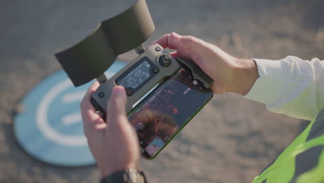 a man stands outside and hold a controller and looks at it