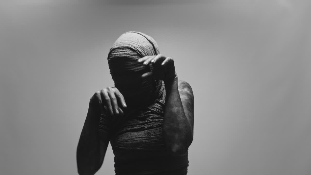 A mummified woman against the bright background moves erratically