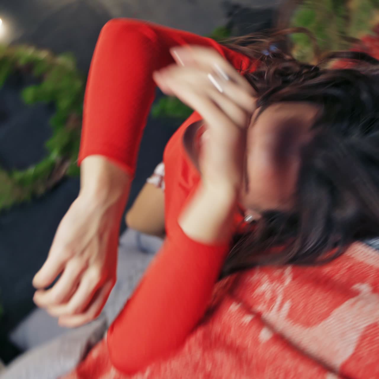 Nice brunette girl in red knitted sweater on the background of a New year decorated room. Presents and christmass balls near bed