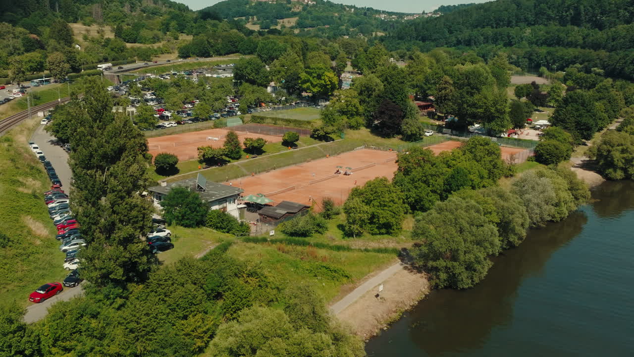 Drone orbit around the Neckargemünd town sports field area built as riverside recreation park with green trees, Baden-Württemberg, Germany