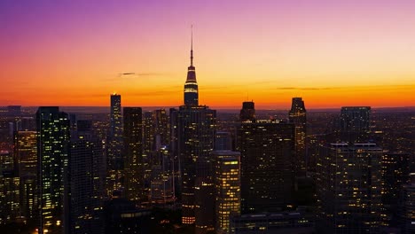 the empire state building is towering over the new york city skyline, illuminated by the warm glow of the setting sun