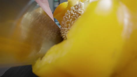 a chef is slicing a yellow pepper on a cutting board