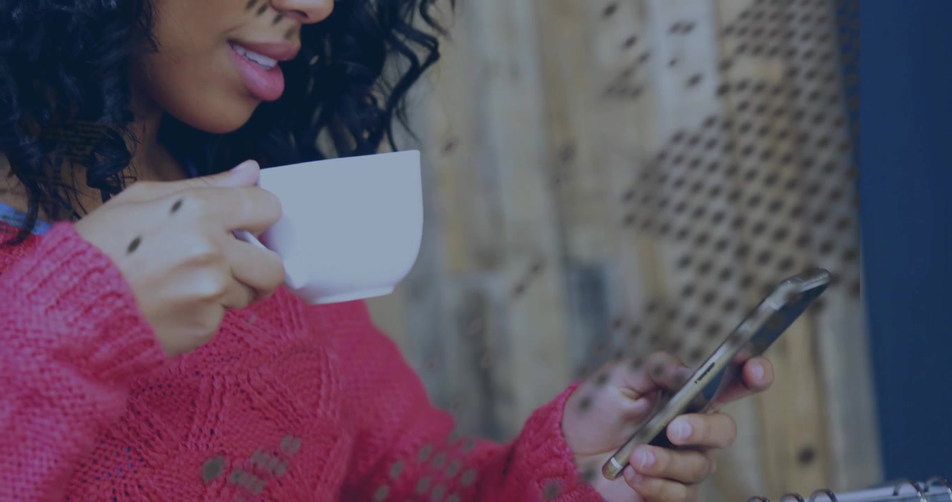 Woman tapping smartphone for business planning on ring-binder while sipping coffee in coffee shop
