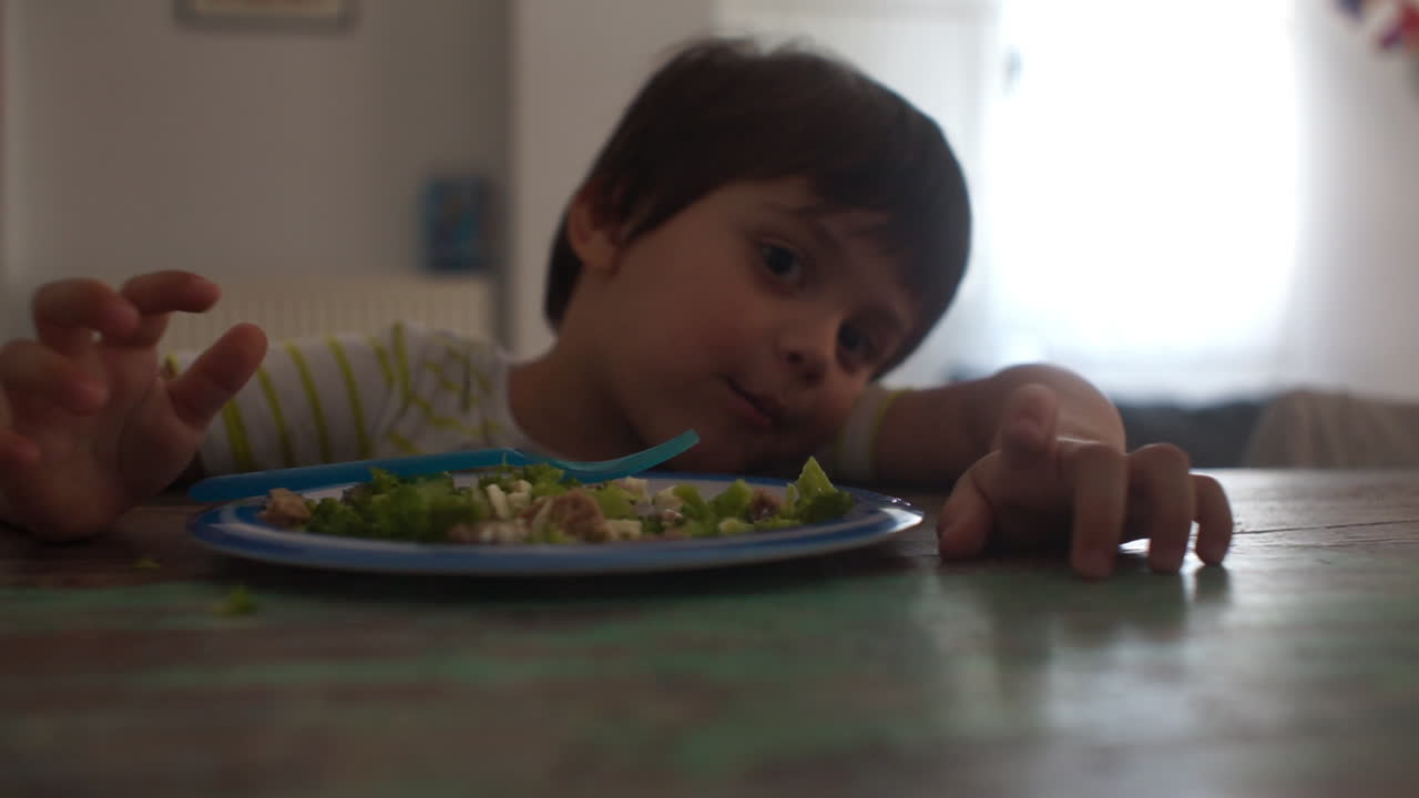 Filmato in primo piano di un bambino che mangia hamburger di manzo e broccoli a casa.