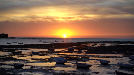 Beautiful-scenery-at-beach-in-Cadiz,-Spain-with-small-fishing-boat-silhouettes