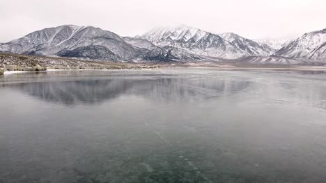 無人機在晴朗的克勞利湖上空飛翔,背景是雪山,在雲<unk>的冬天 - 美國,加州