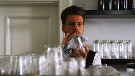 Bar-tender-cleaning-glass-at-counter-in-restaurant