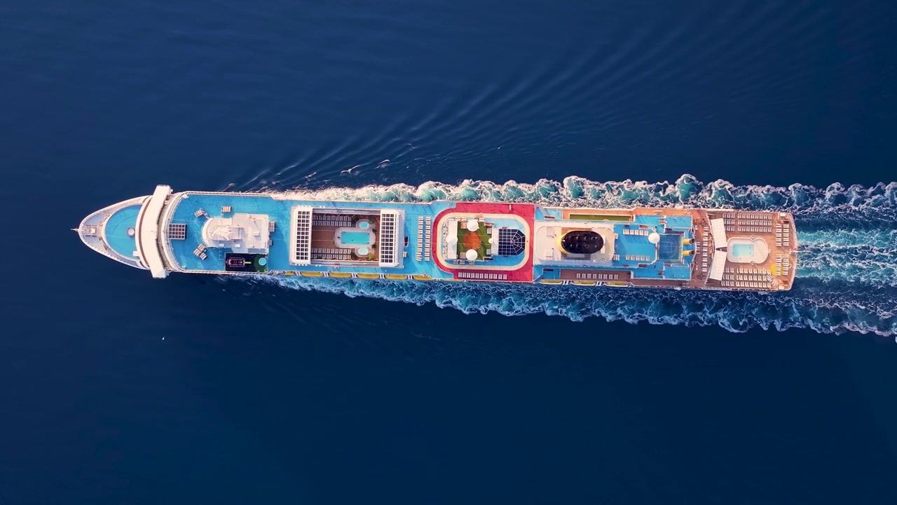 Maestosa grande nave da crociera che naviga su acque calme e blu. Vista aerea dall'alto del transatlantico che crea una scia mentre si muove attraverso l'oceano.